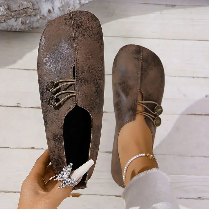 Top view of a brown soft suede loafer held by hand and one worn by model with a pearl anklet