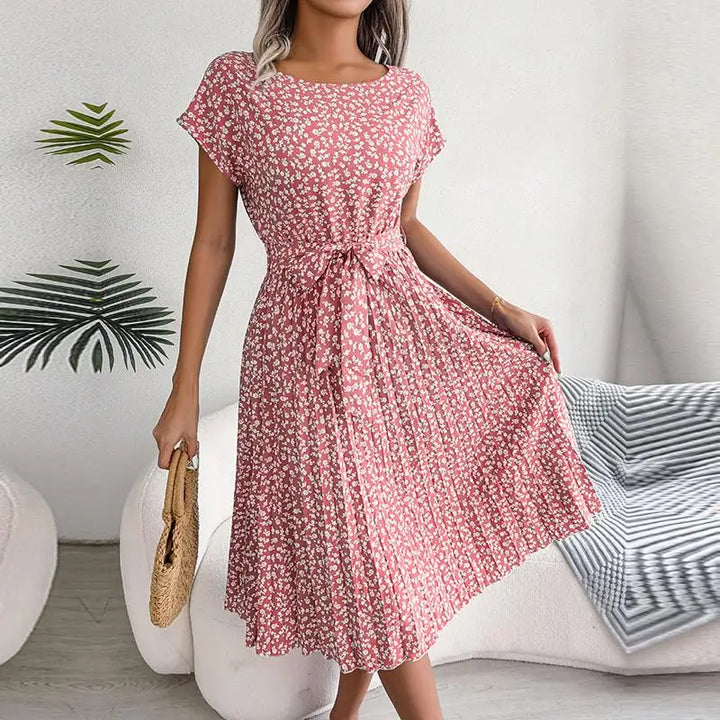 Front view of a model wearing a pink floral pleated maxi dress with a tie waist and short sleeves