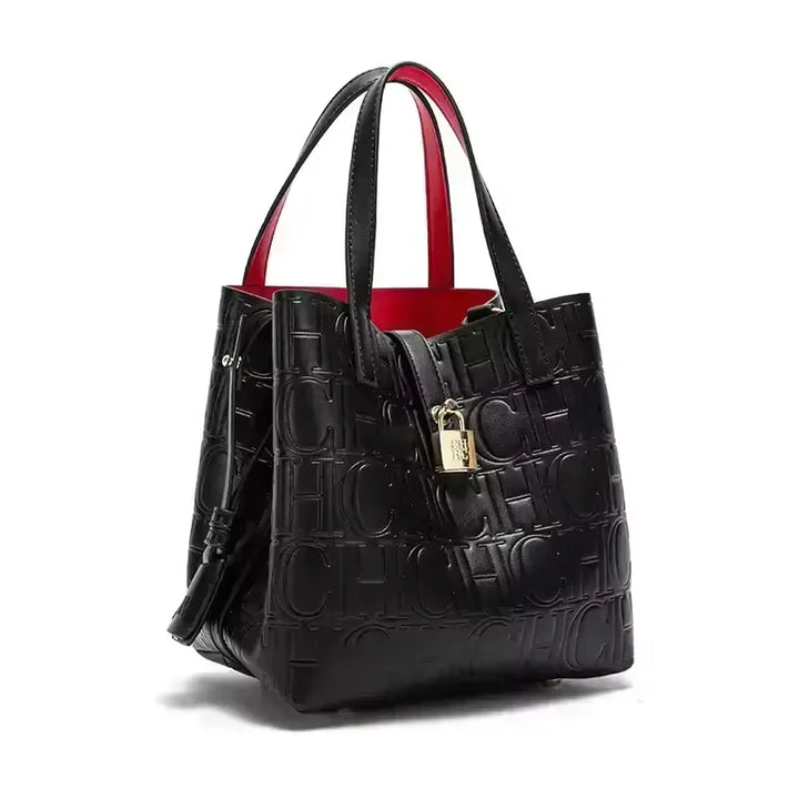Three quarter view of a black Kara Classic Large Bucket Handbag with red lining and a gold padlock
