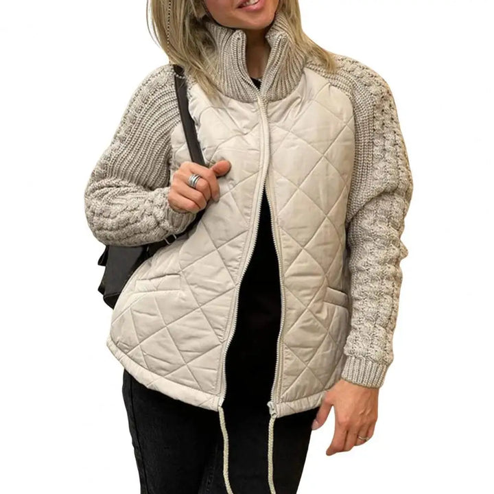 Front view worn by model, a woman wearing a beige quilted knit jacket with an open zip and high collar