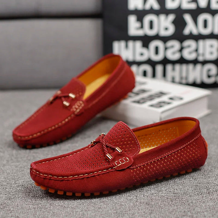 Pair of red Austin slip-on loafers with perforated detail, orange sole, and decorative bow