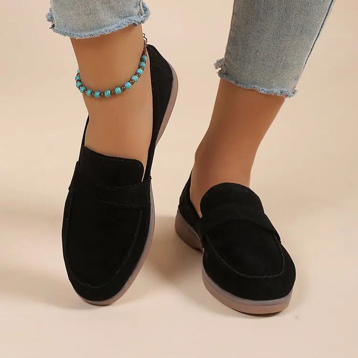 Close up worn by model, black suede loafers with brown soles, light blue jeans, and a turquoise anklet