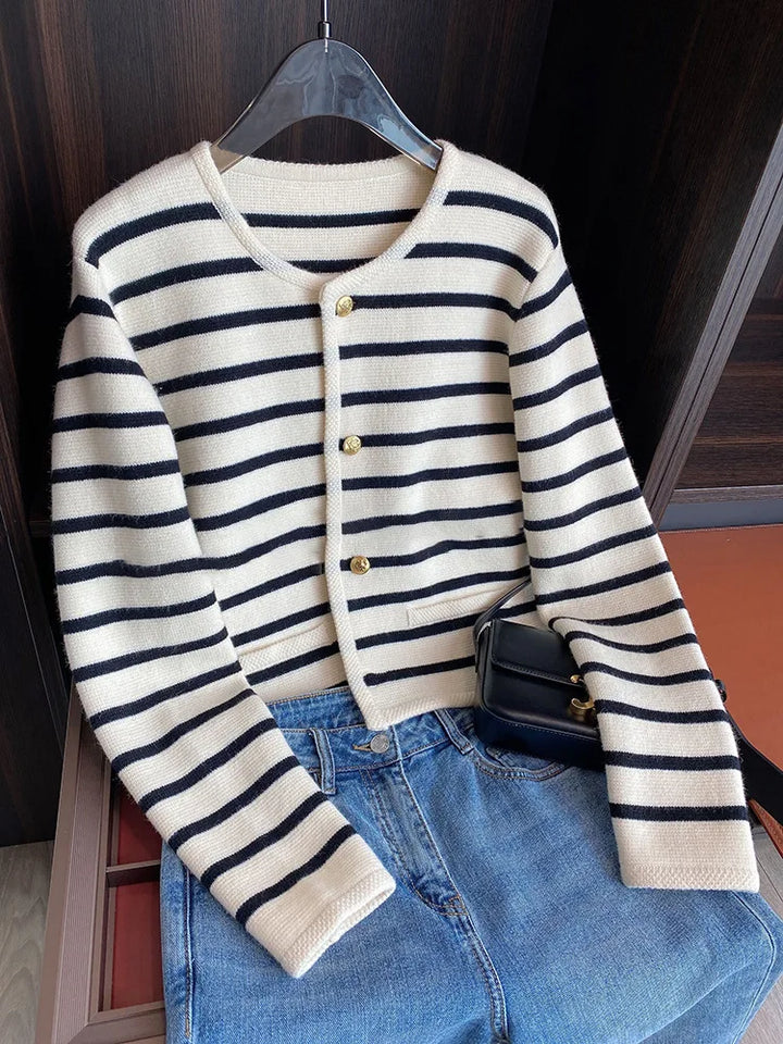 Front view of a cream striped knit crop cardigan with black stripes, gold buttons, jeans and a black handbag