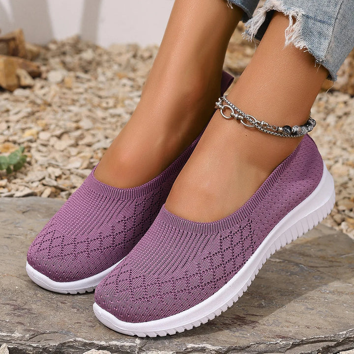 Close up of a model wearing purple breathable mesh flats with white soles and a silver ankle bracelet