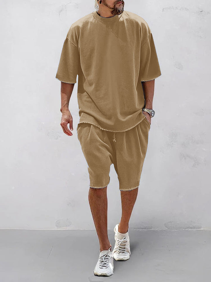 Front view of a model wearing a tan relaxed fit shorts and matching t-shirt with raw edge hems