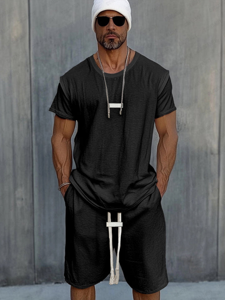 Front view of a model in a black Essential Sport T-shirt and Shorts set with hands in pockets