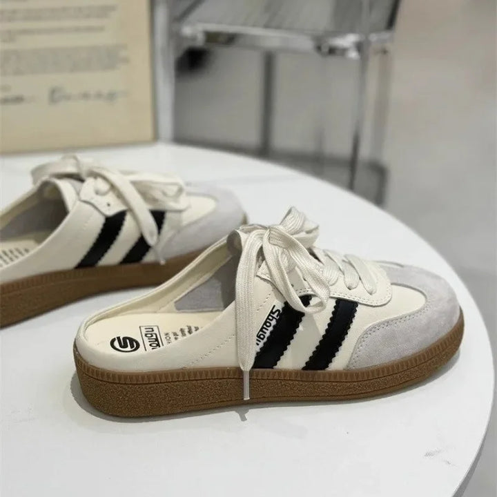 Side view of two casual platform slip-on mules with beige uppers, black stripes and a patchwork design