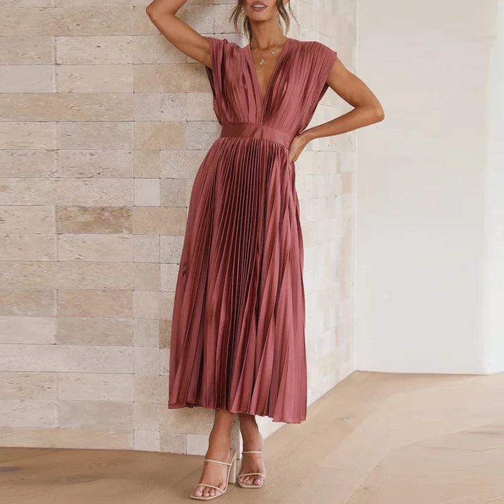 Front view, model wearing a dusty pink Felicia pleated dress with a deep V neckline and cap sleeves