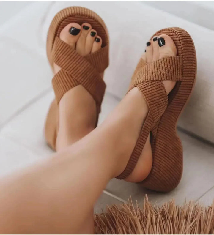 Three quarter view of brown modern chunky Roman sandals with velvet upper, worn by model, showing black toenails