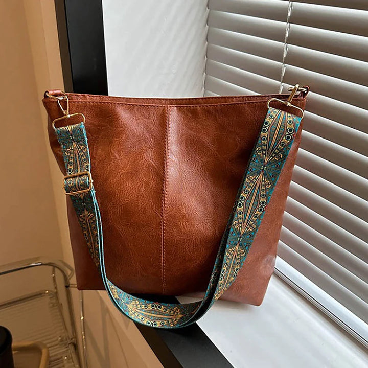 Front view of a brown PU leather vintage bucket shoulder bag with a colourful patterned strap