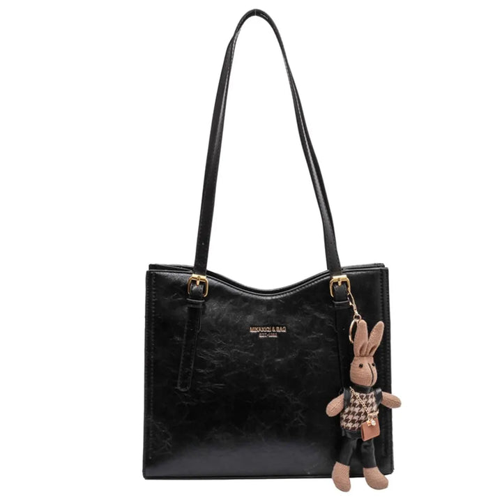 Front view of the black vegan leather Gwen bag with a cute rabbit charm hanging from a strap