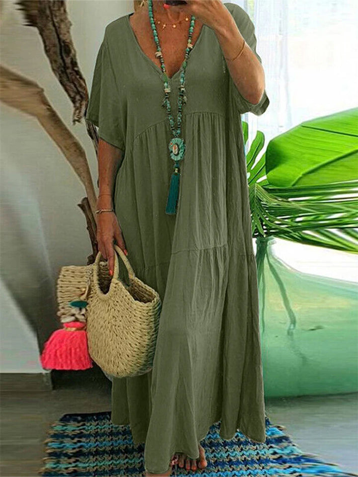 Front view worn by model, a plus size V-neck midi dress in olive green with pleated detail and short sleeves