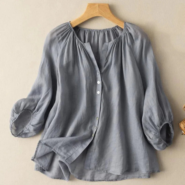 Front view of a grey lightweight linen blouse with elegant ruching on a hanger