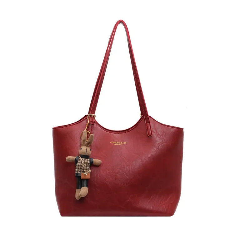 Front view of the Piper vegan leather tote bag in a rich dark red with a cute bunny charm attached