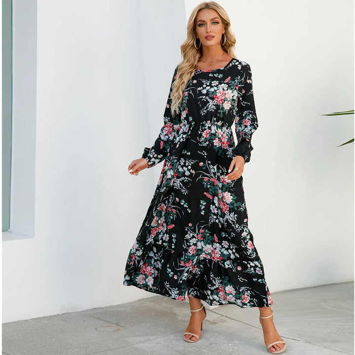 Front view, worn by model, a black bohemian chiffon maxi dress with pink and green floral print, and heels