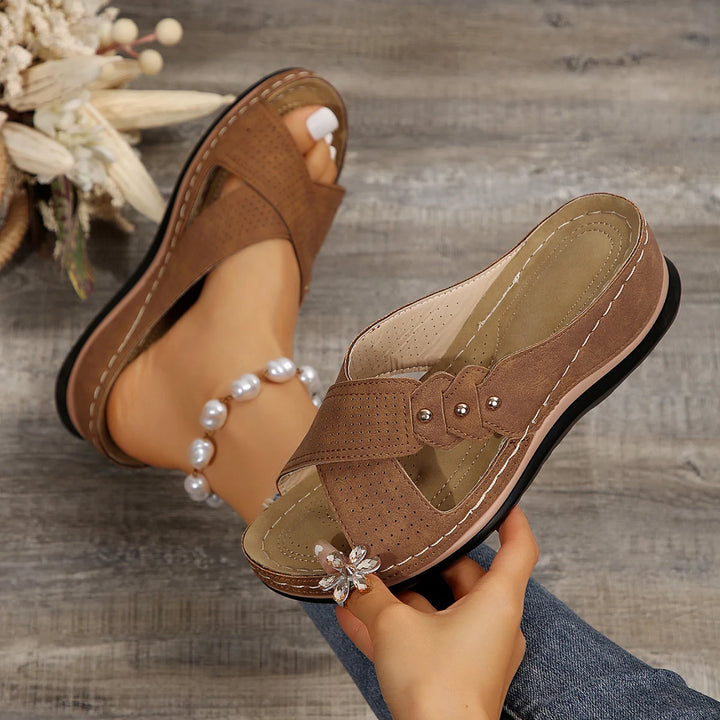 Close up of a pair of brown Gabrielle Summer Slides, one worn on a foot with a pearl anklet