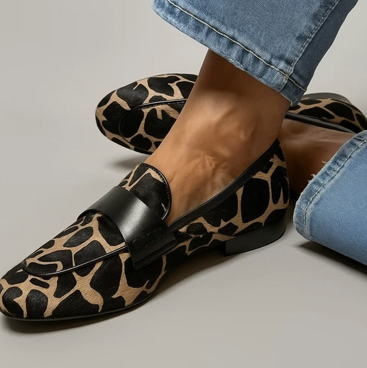Worn by model, close up of a foot wearing a black and tan animal print loafer with blue jeans