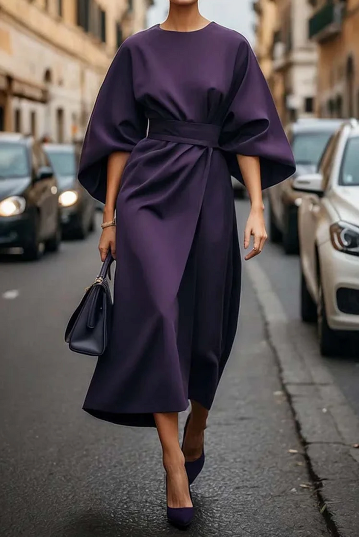 Front view of a model in a purple elegant knee-length dress with wide lantern sleeves and a wrap skirt design