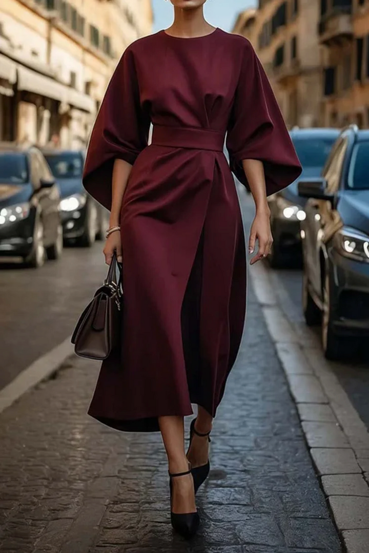 Front view of a model in a burgundy elegant knee-length dress with wide lantern sleeves and a wrap skirt design