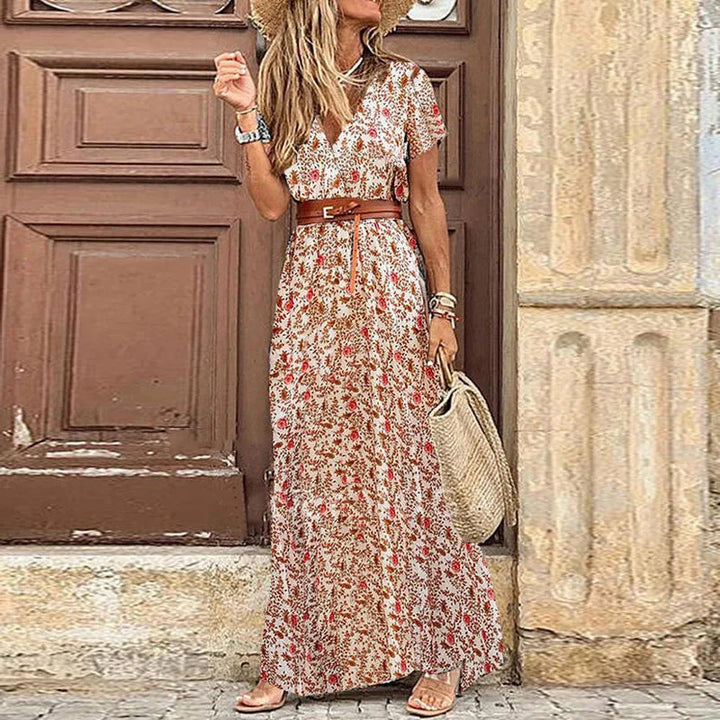 Front view of a model wearing the floral pleated midi dress with a straw hat and woven bag