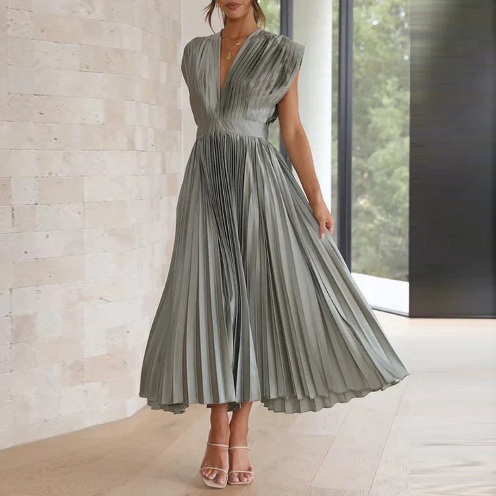 Front view, model wearing a sage green Felicia pleated dress with a deep V neckline and cap sleeves