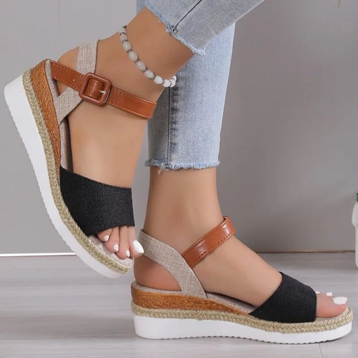 Vera Retro Wedge Sandals worn by model, a pair of black and tan sandals with a woven espadrille wedge sole