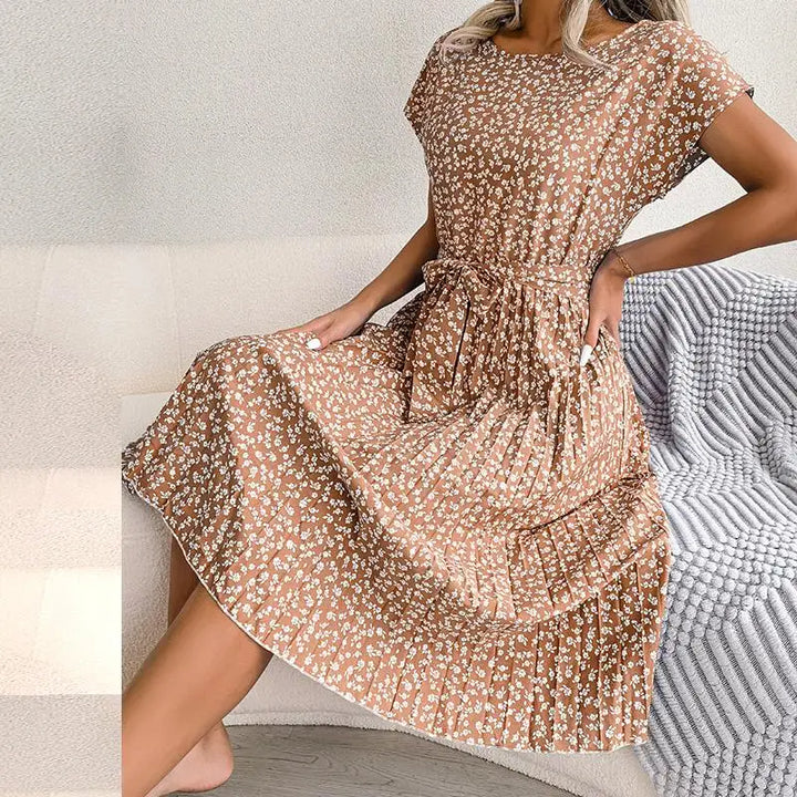Side view of a model wearing a brown floral pleated maxi dress with a tie waist and short sleeves