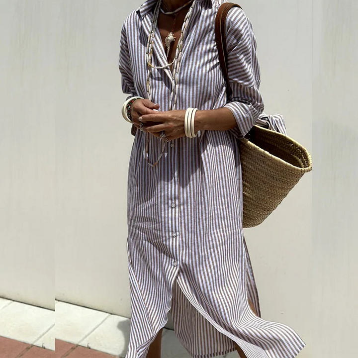 Detail view of a model wearing a striped shirt dress, layered necklaces, and a straw bag