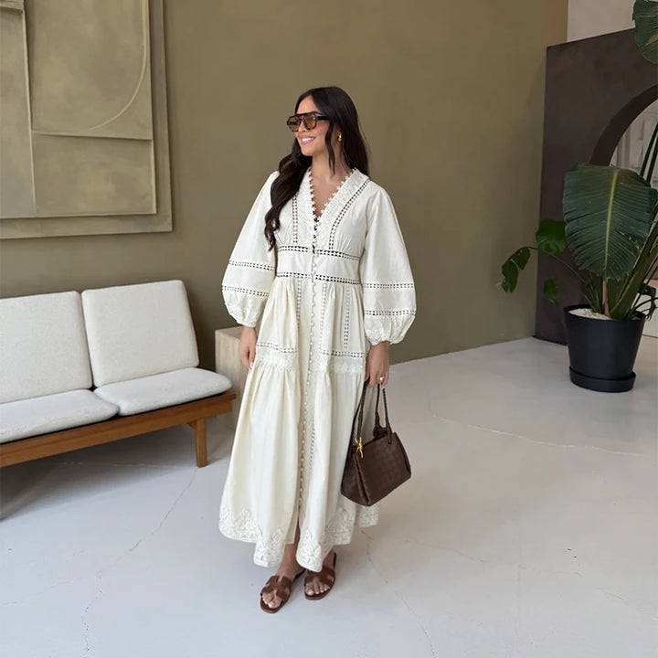 Three quarter view, worn by model, of an elegant cream lace patchwork dress with puff sleeves and brown sandals