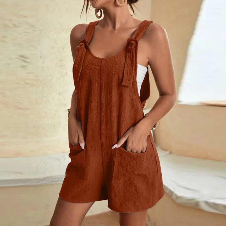 Side view of a woman wearing a casual sleeveless summer romper in rust with tie straps and pockets