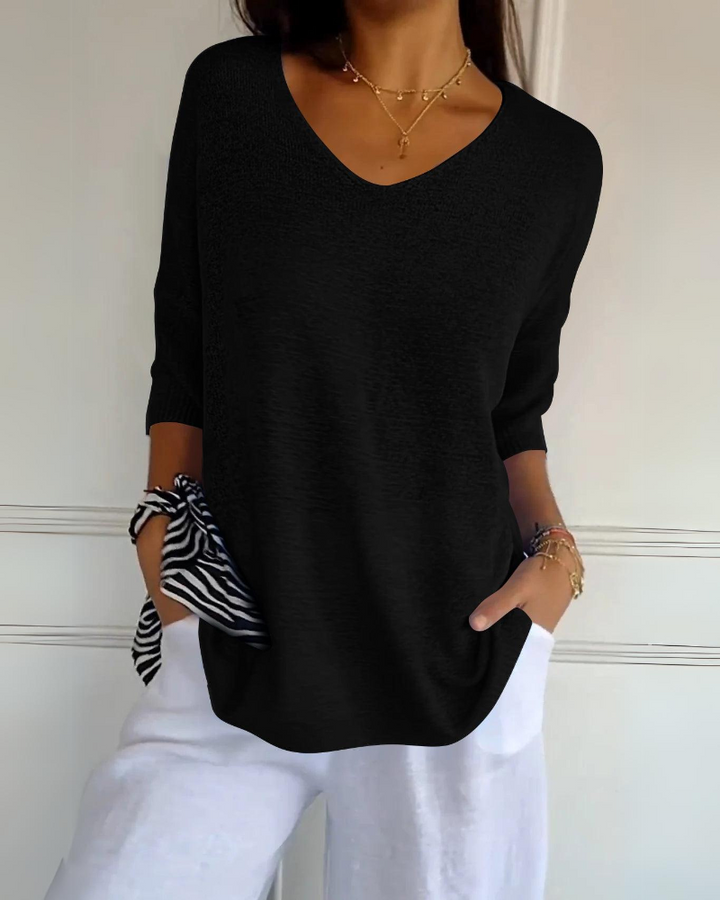 Front view of a model wearing a black breathable cotton top with a V neckline and white linen pants with pockets