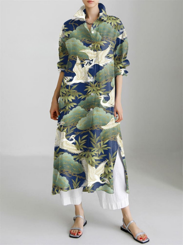 Front view of a model wearing the pattern long sleeve slit shirt dress with cranes and trees on a navy background