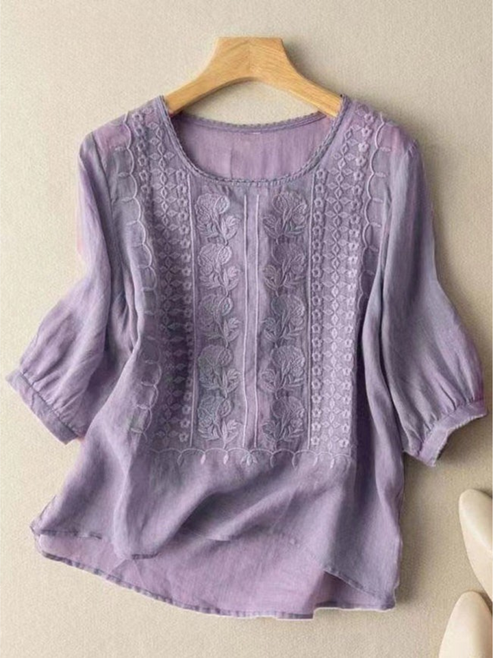 Front view of a purple mid sleeve cotton linen embroidery blouse on a hanger, with cream shoes
