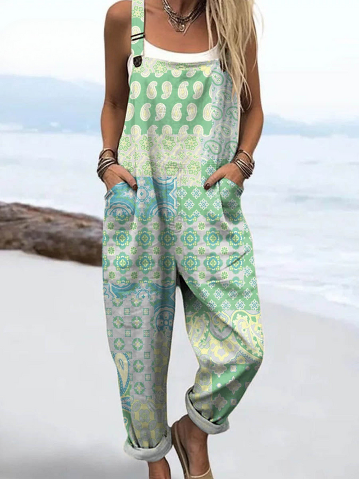 Front view, model wearing a vintage cotton wide leg jumpsuit in a green and blue pattern on a beach