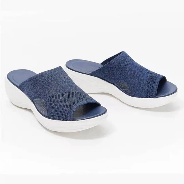 Pair of orthopaedic stretch sandals, dark blue upper, dark blue footbed, white wavy sole, on white background