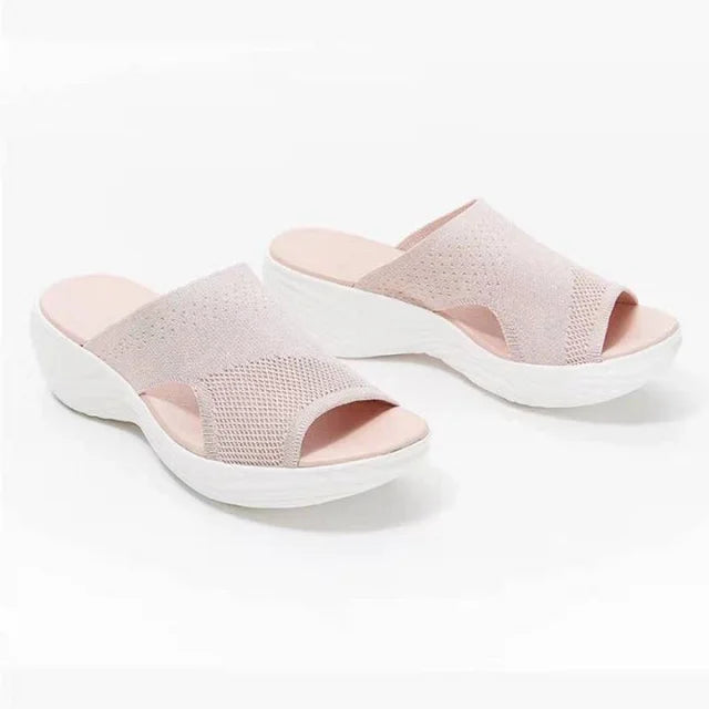 Pair of orthopaedic stretch sandals, light pink upper, light pink footbed, white wavy sole, on white background