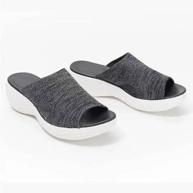 Pair of orthopaedic stretch sandals, dark grey upper, black footbed, white wavy sole, on white background