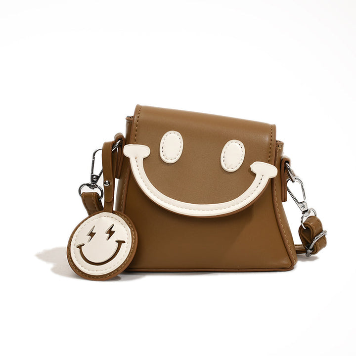 Front view of a brown Bright Smile crossbody bag with white smiley face and keyring against a white background