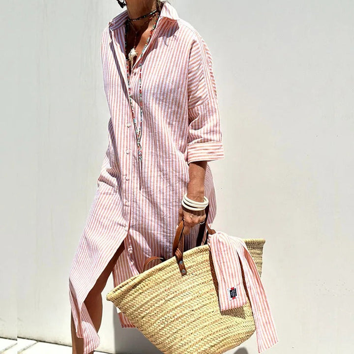 Front view, model wearing a pink and white striped shirt dress, holding a straw bag and wearing beaded necklaces