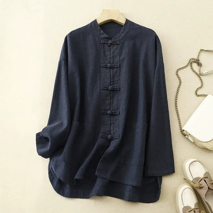 Front view of a navy linen shirt with a mandarin collar and frog button closures, hanging on a timber hanger