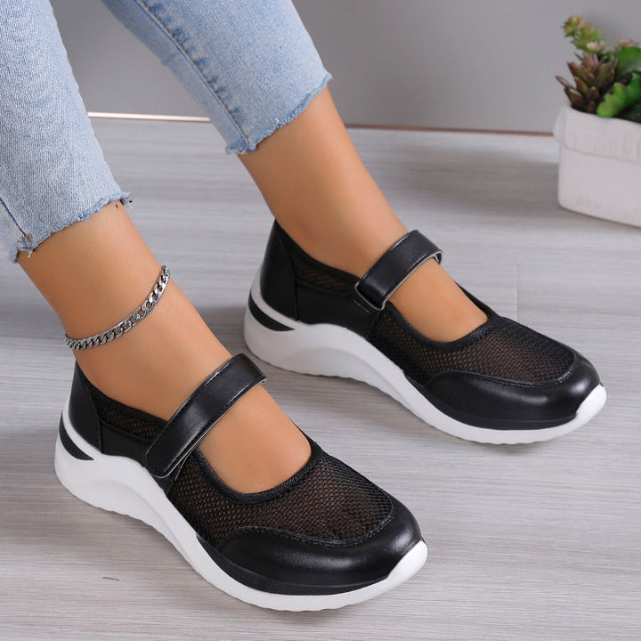 Close up of black orthopedic Mary Jane shoes with mesh detail and white soles on a model
