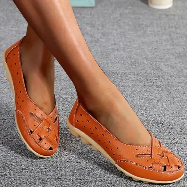 Worn by model, a pair of orange breathable leather loafers with woven toe and perforated sides