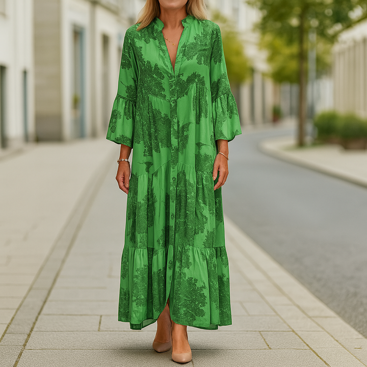 Front view of an elegant floral dress worn by model, a long green cotton blend dress with tiered skirt and bell sleeves