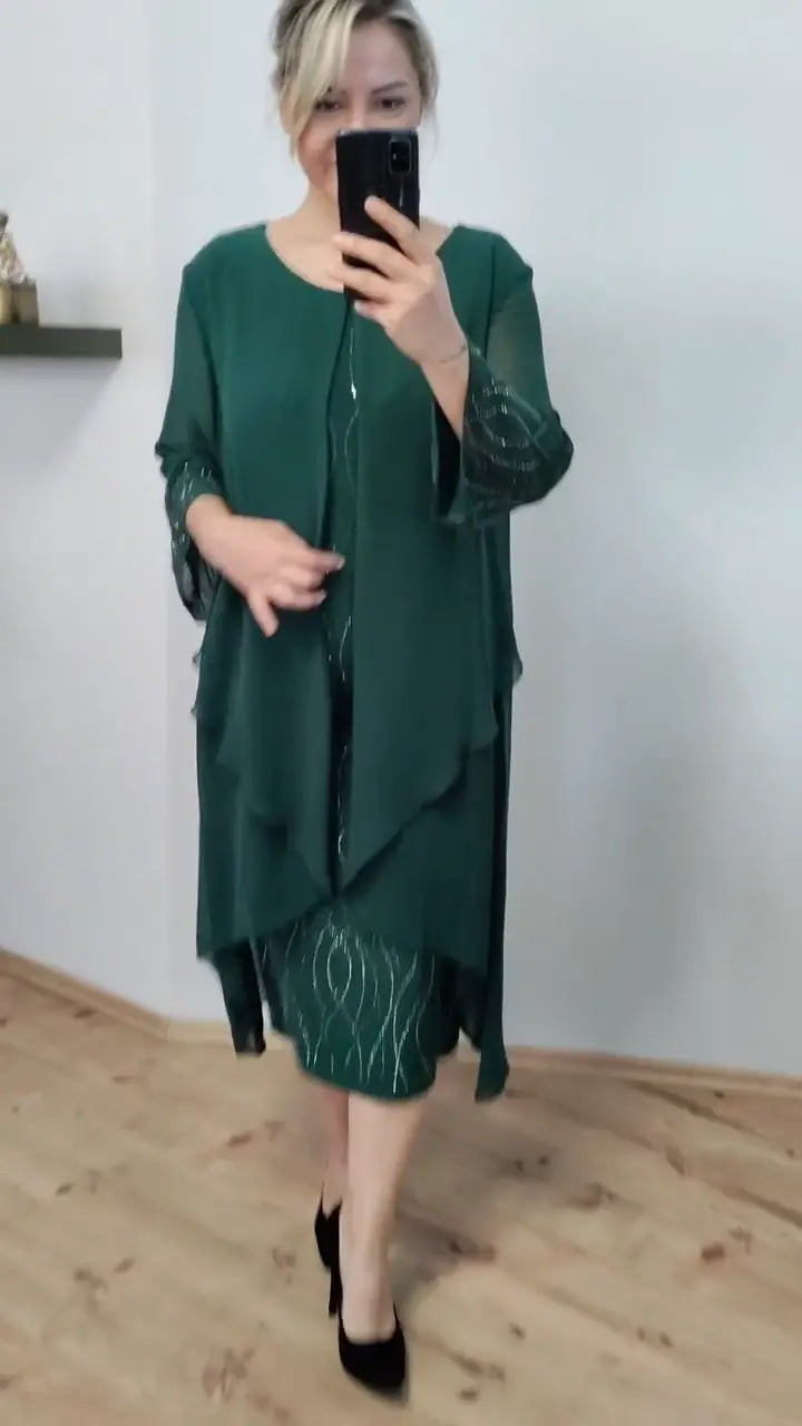 Front view of a model in an elegant green chiffon ruffle midi dress taking a mirror selfie