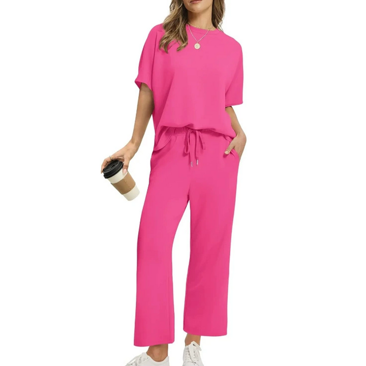 Front view, model wearing a comfortable two-piece casual top and pants set in bright pink with a coffee cup