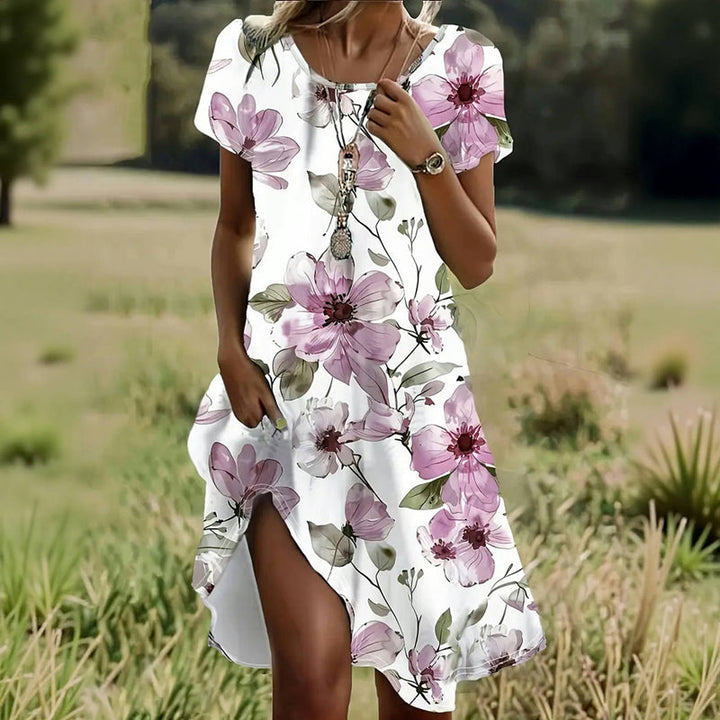 Front view of a model wearing a casual floral A-line dress with short sleeves and a side split in a field
