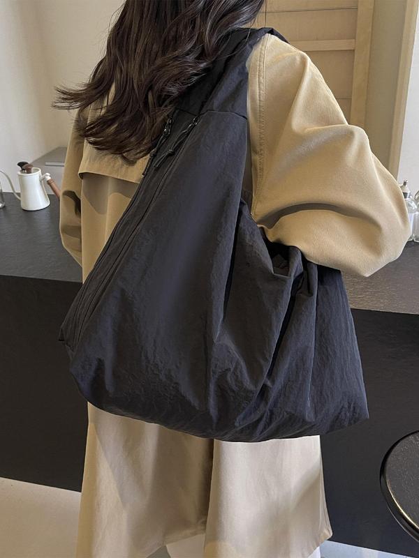 Back view, worn by model, of a black Lush Everyday Tote Bag over a beige trench coat