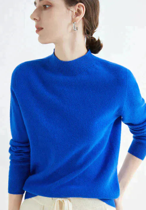Three quarter view, model wearing a bright blue cashmere mock-neck jumper with ribbed collar and cuffs
