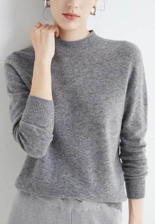 Front view, model wearing a grey cashmere mock-neck jumper with ribbed collar and cuffs, light grey skirt