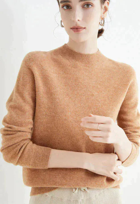 Close up, model wearing a brown cashmere mock-neck jumper with ribbed collar and cuffs, light coloured pants